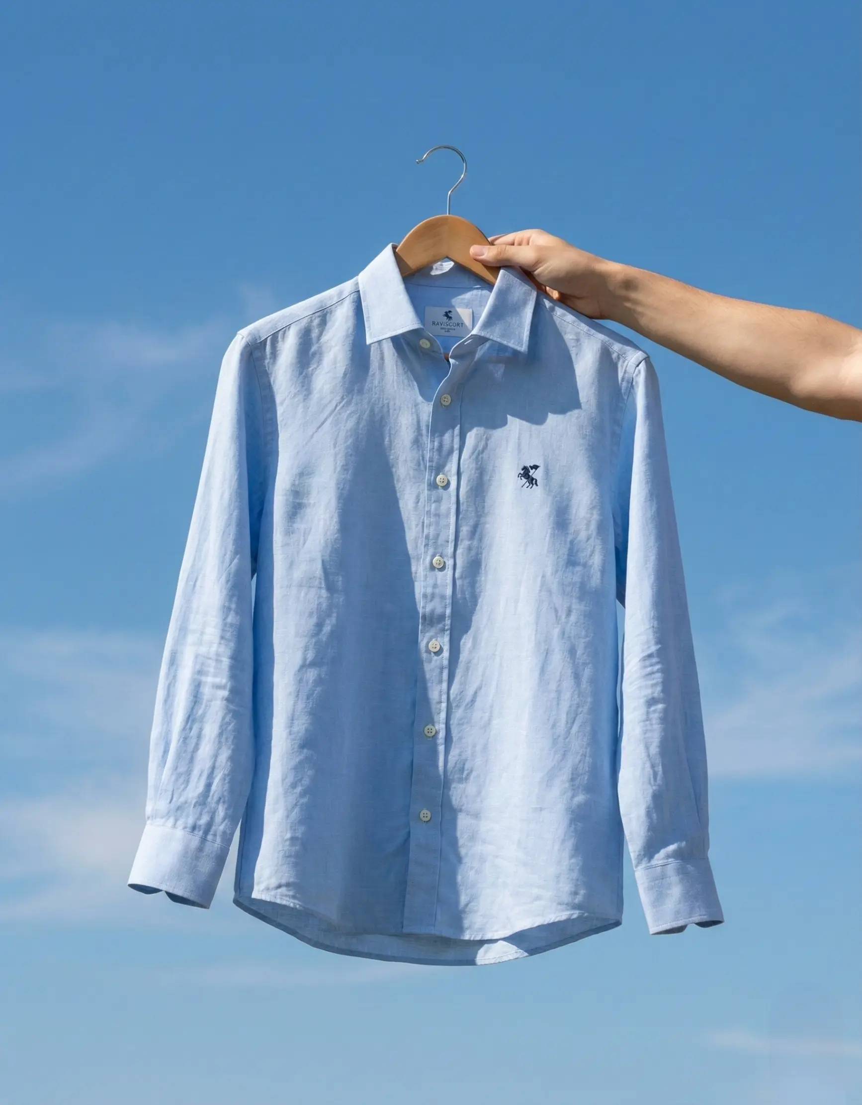 Sky-blue linen shirt held up against a clear sky
